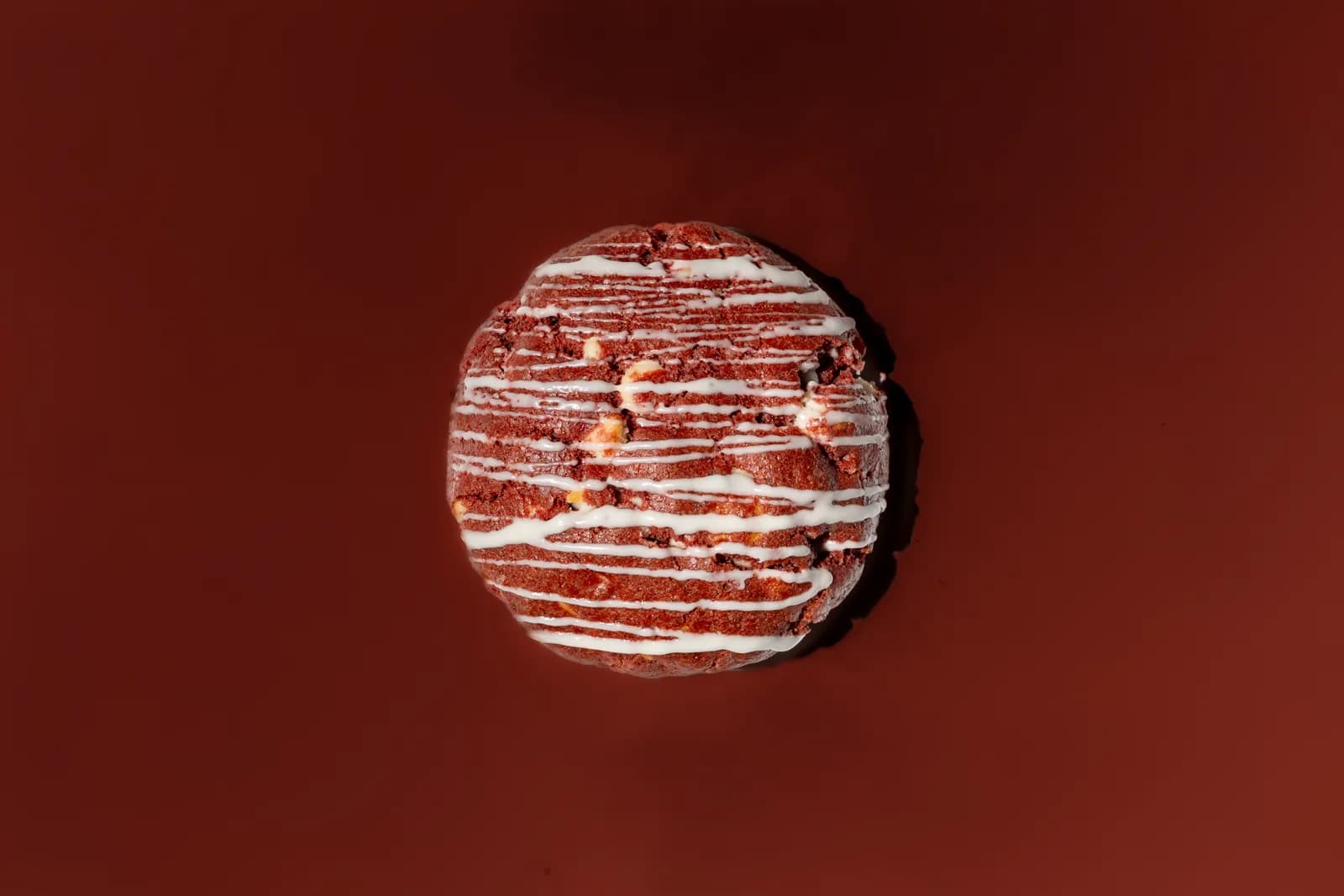 A filled cookie broken open on a deep red seamless background.