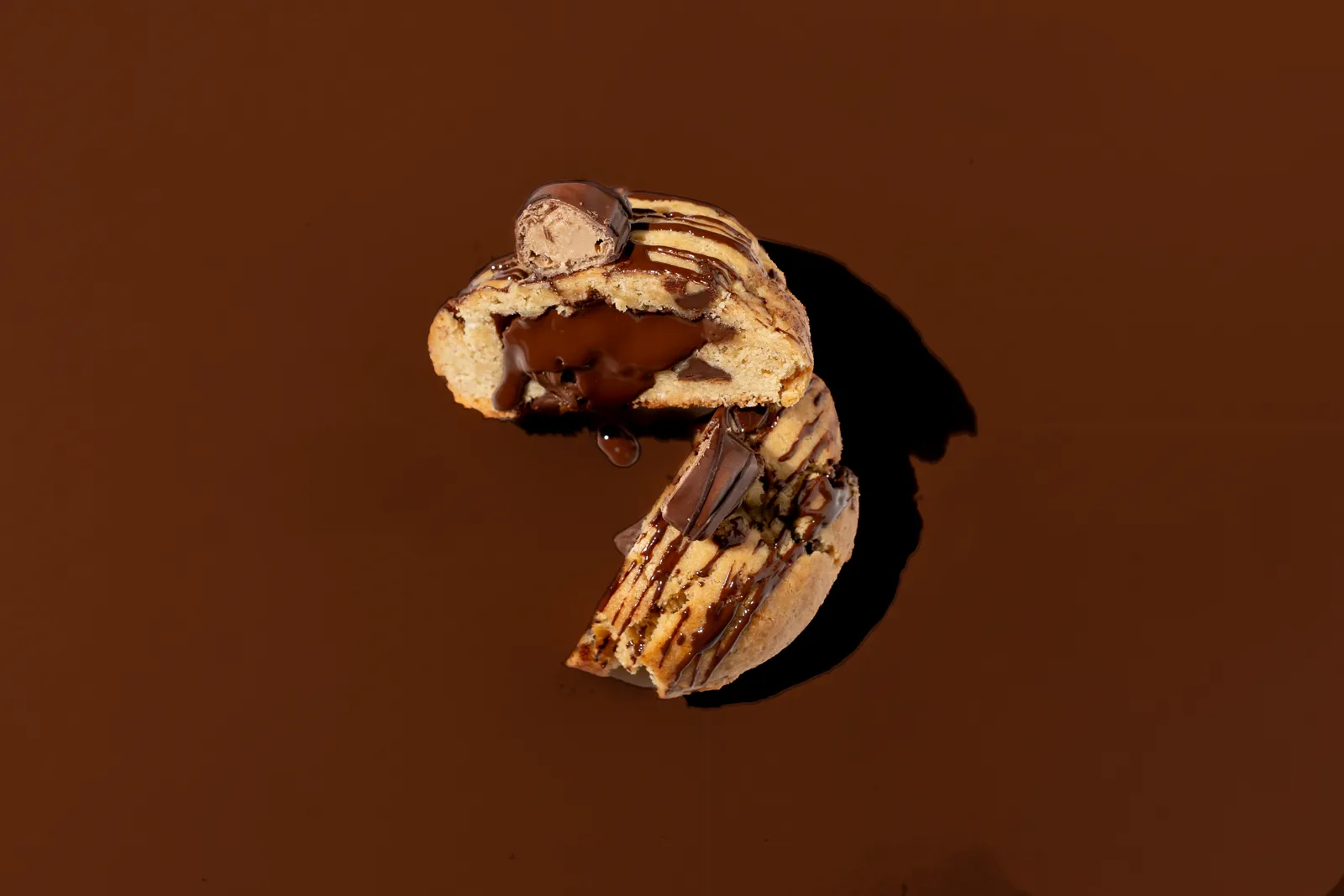 Two cookies stacked on a warm brown background, filling pulling between them.