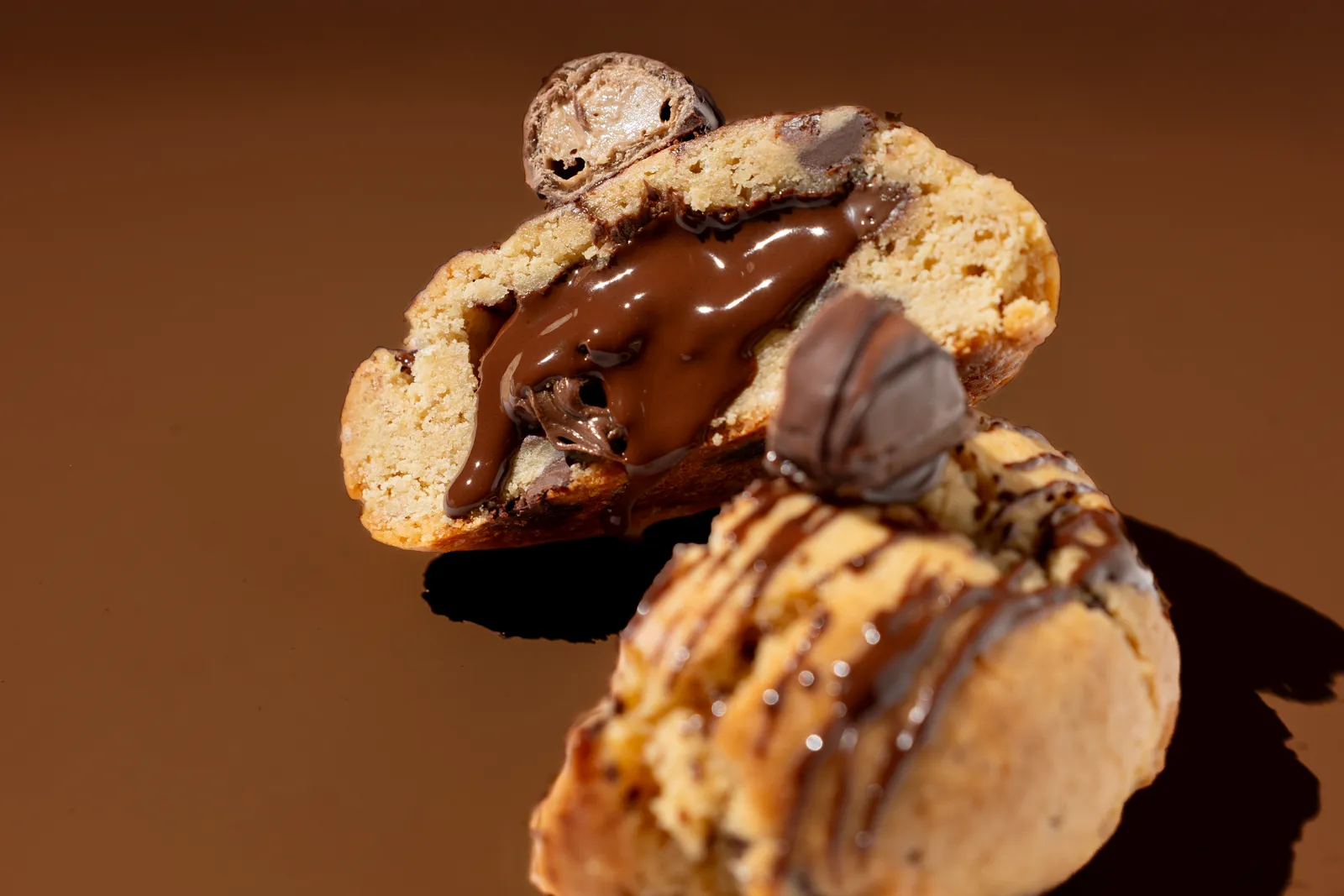A chocolate-filled cookie on a brown background, lit from the side.