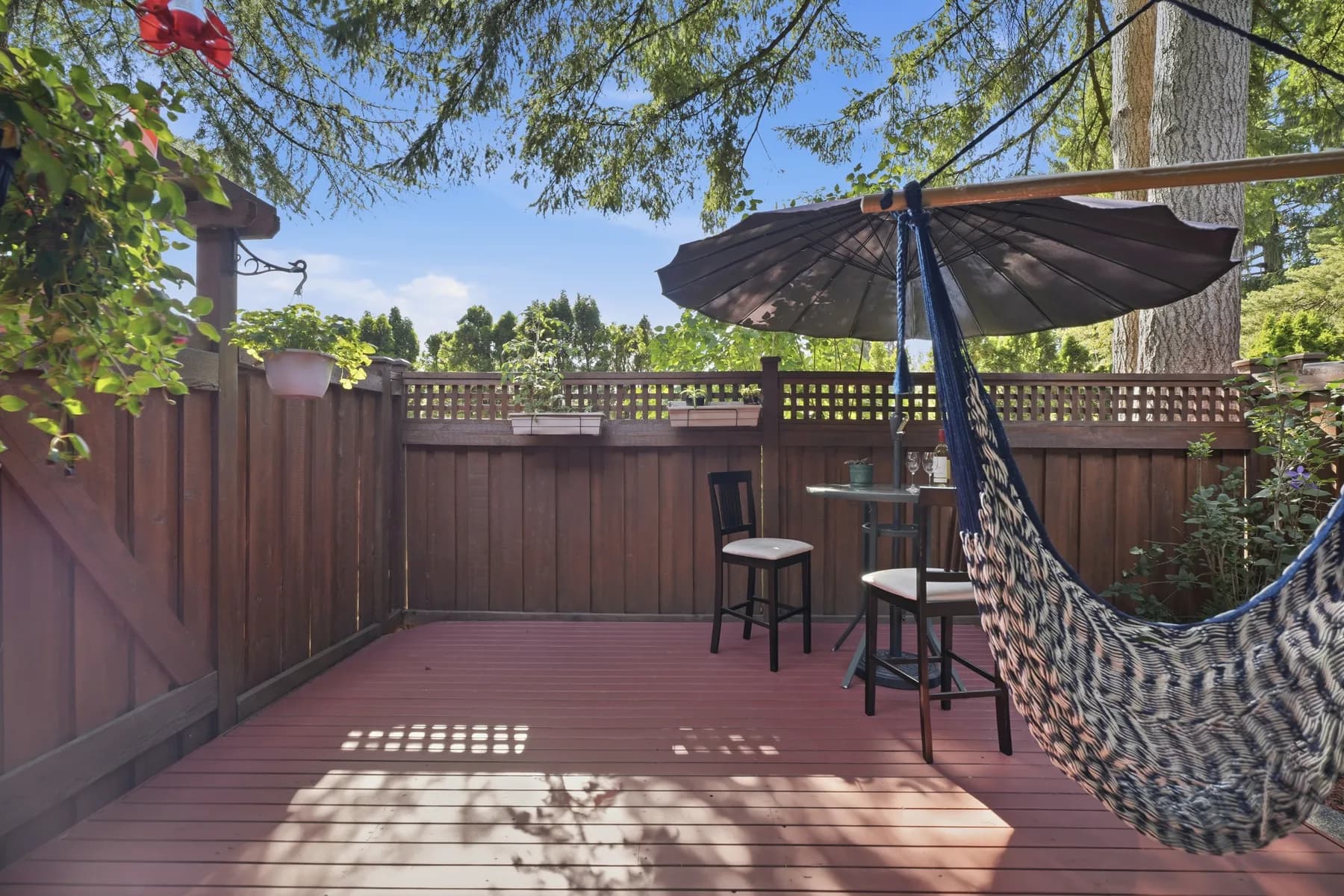 An aerial placing the house against the Metrotown skyline, then the interior: a galley kitchen, dining through to the deck, and a garden held in by mature trees.