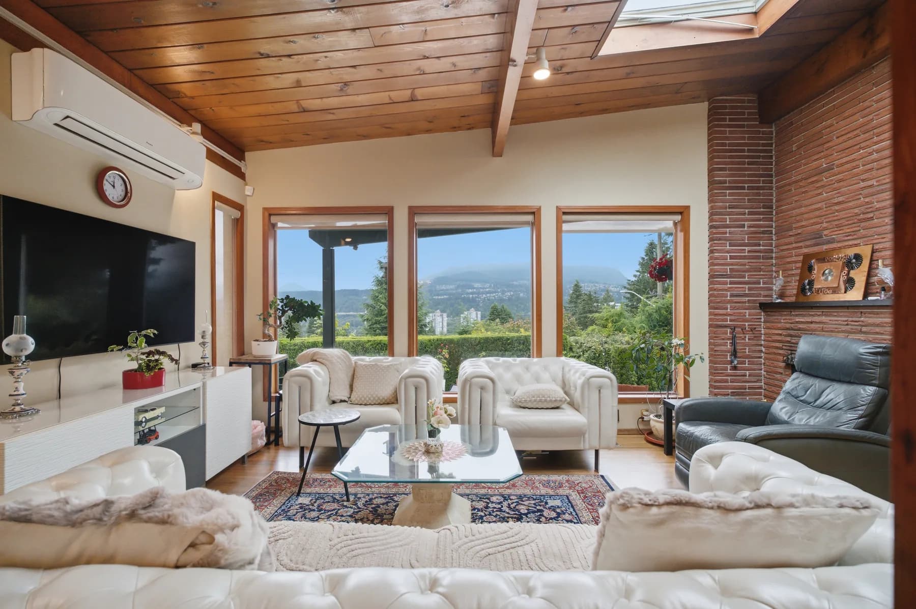 Shot from the air and the ground: the inlet, the towers and the ridge behind the property, then a cedar-ceilinged living space opening onto the same outlook.