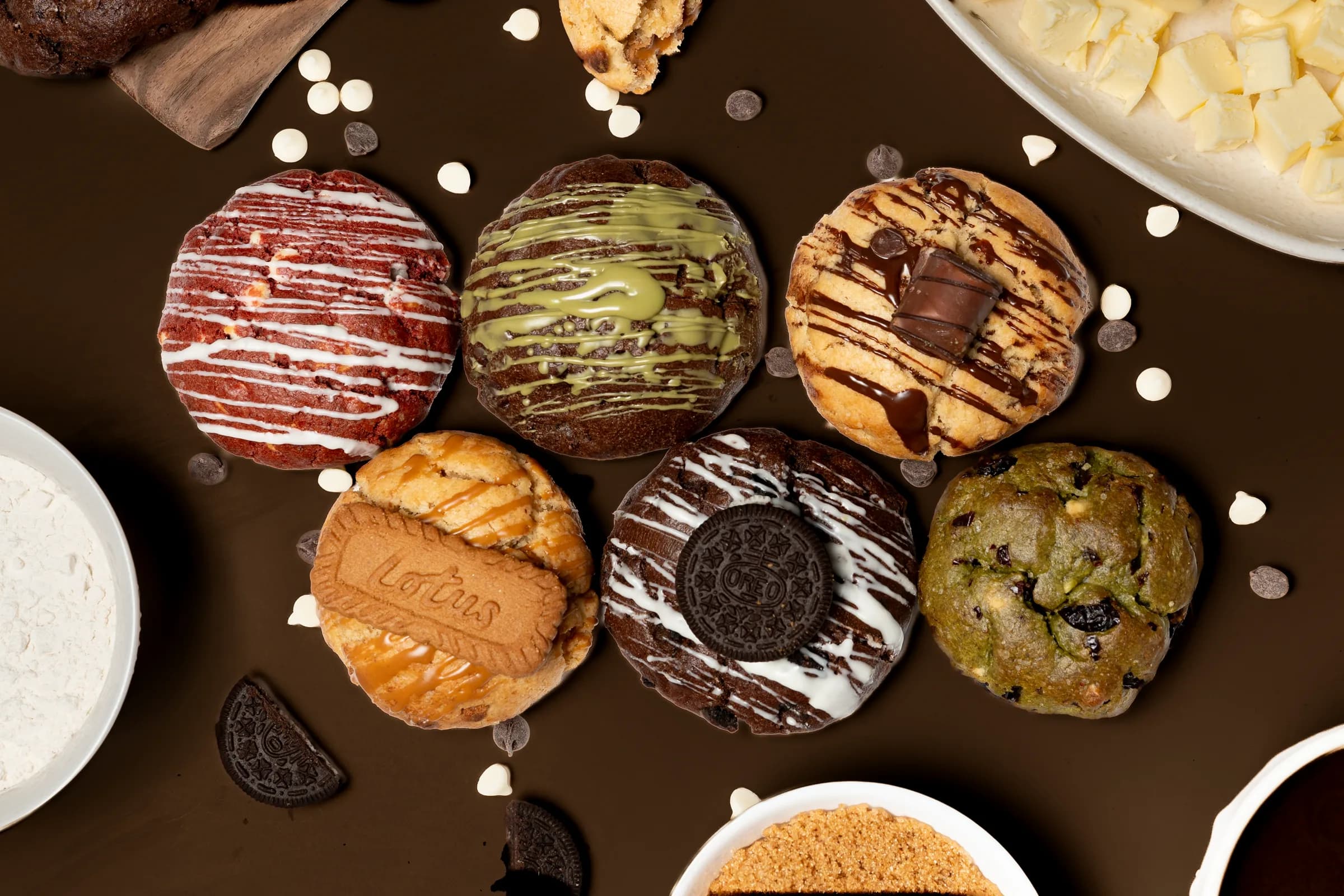 Overhead product photograph of a bakery's cookie range on a brown ground.